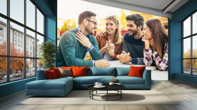 Group of four friends having fun a coffee together. Two women and two men at cafe talking laughing and enjoying their time Wall mural