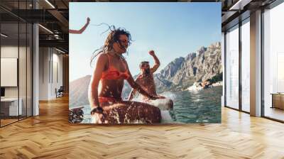 Group of friends jumping off the pier into the sea. Selective focus Wall mural