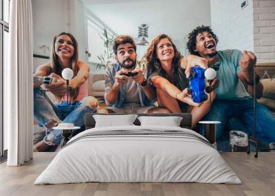 Group of friends play video games together at home, having fun. Wall mural