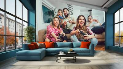 Group of friends play video games together at home, having fun. Wall mural