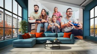 Group of friends play video games together at home, having fun. Wall mural