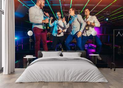 Group of smiling male friends having fun in night club Wall mural