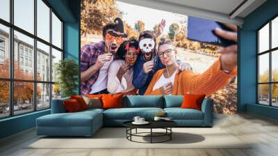 Group of young people hangout in the park.They are make selfie photo with halloween props. Wall mural