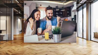 Happy couple doing business together working at home on the laptop. Wall mural