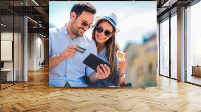 Happy couple paying on line with credit card and digital tablet on the street Wall mural