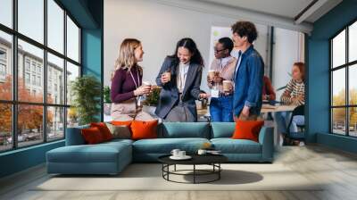 Happy diverse colleagues have fun at lunch break in office, smiling multiracial employees laugh and talk  drinking coffee Wall mural