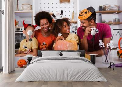 Happy family mother father and children prepare for Halloween. They are carving pumpkin. Wall mural