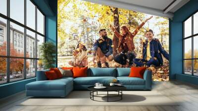 Happy family throwing colorful autumn leaves in the park. Wall mural