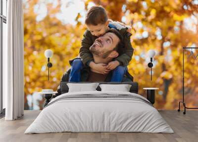 Happy father and little son playing and having fun outdoors over autumn park background Wall mural