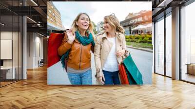 Happy friends shopping. Two beautiful young women enjoying shopping in the city. Wall mural