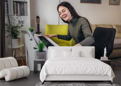 Happy girl is playing piano for her hobby relax time in home living room. Portrait Of Smiling Teenage Girl At Home Playing The Piano Wall mural