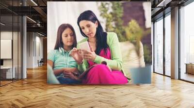 Happy mother and her cute teen daughter are looking at mobile ph Wall mural