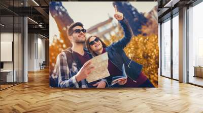 Happy tourists couple holding map in the autumn park Wall mural