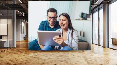 Happy young couple enjoying time online on digital tablet. Wall mural