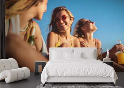 Happy young women sitting on the beach. Group of friends enjoying on beach holiday. Wall mural