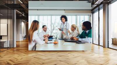 Medical team sitting and discussing at the table in the office. Wall mural