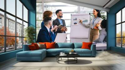 Multiracial businesss people showing their colleagues diagrams and graphics on a business meeting. Talk about growth of the firm and statistics. Wall mural