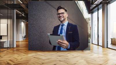 Portrait of businessman in glasses holding tablet Wall mural