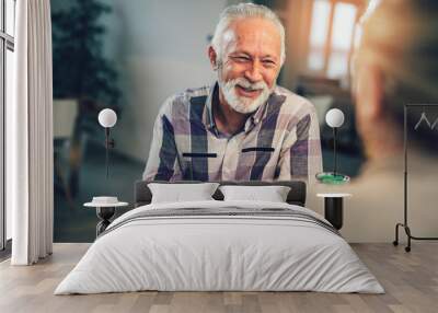 Portrait of happy senior man sitting at breakfast table, smiling at camera, sitting with wife. Wall mural