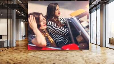 Portrait of two beautiful sexy fashion woman model sitting in luxury retro cabriolet car Wall mural