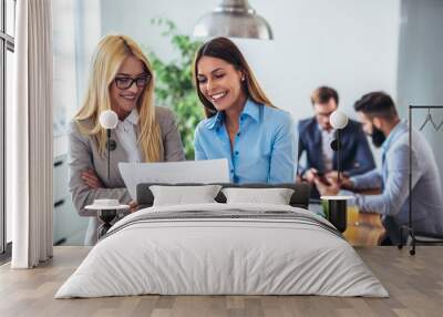 Portrait of two young businesswoman while colleague in background Wall mural