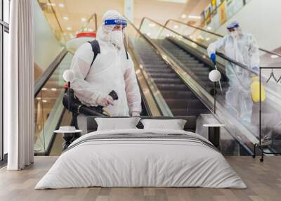 Professional workers in hazmat suits disinfecting indoor of mall, pandemic health risk, coronavirus Wall mural