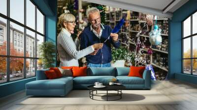 Senior couple at Christmas Market buying decor toys and balls. Concept of Christmas and New Year shopping. Wall mural