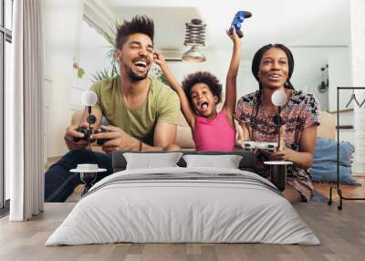 Smiling family sitting on the couch together playing video games Wall mural