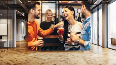 Smiling young friends drinking craft beer in pub Wall mural