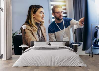 Successful young couple man and woman working on PC computer together while sitting at table at home Wall mural