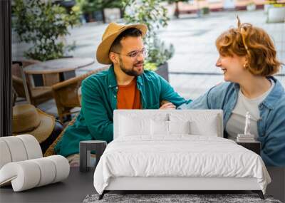 Tourist couple sits in a cafe. Hold hands and talk to each other. Taking a break from exploring the city. Wall mural