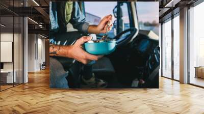 Truck driver taking a break from long drive to eat some food from container. Wall mural