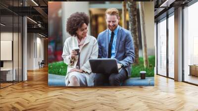 Two business people in an informal conversation in front of a business building using laptop and drink coffee Wall mural