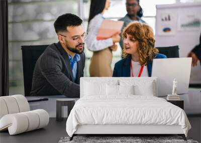 Two business people working together on laptops and tablets in office. Wall mural