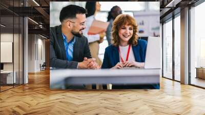 Two business people working together on laptops and tablets in office. Wall mural