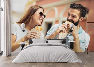 Young couple is eating sandwiches and having a great time Wall mural