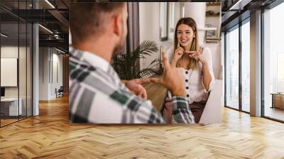 Young couple talking using sign language at home. Wall mural