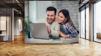 Young Couple Using Laptop On Desk At Home Wall mural