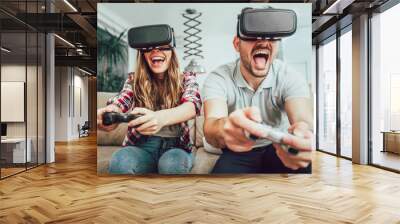 Young funny couple playing video games virtual reality glasses in their apartment Wall mural