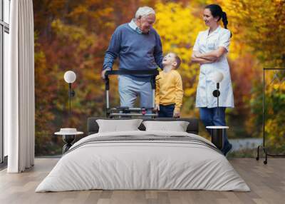 Young grandson spending time in the park with disabled senior grandfather Wall mural