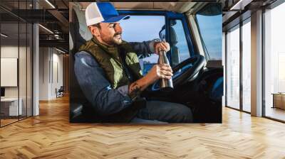 Young handsome man driving long vehicle and drinking coffee so he could get some energy. Wall mural