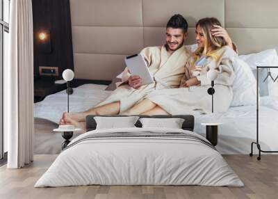 Young happy couple shopping online in luxury hotel room. Wall mural