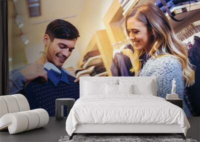 Young man consults with girlfriend while selecting a sweater Wall mural