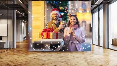 Young romantic couple holding gift box having fun outdoors in winter before Christmas. Wall mural