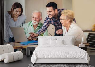 Young volunteers help senior people on the computer. Young people giving senior people introduction to internet Wall mural