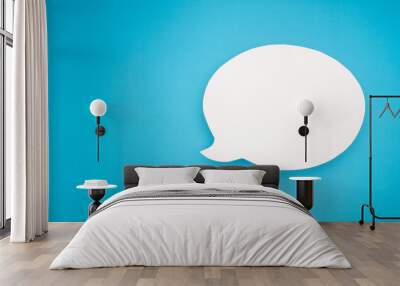 A blank white speech bubble over a light blue background Wall mural