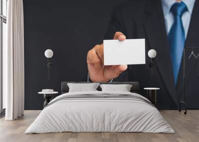 Close-up of a hand businessman holding a blank business card while standing on a gray background Wall mural