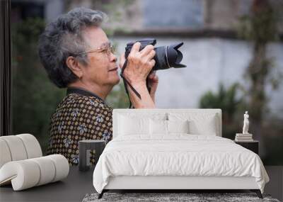 Elderly woman shooting photo by digital camera Wall mural