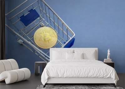 Golden bitcoin in blue metal shopping cart on blue background Wall mural