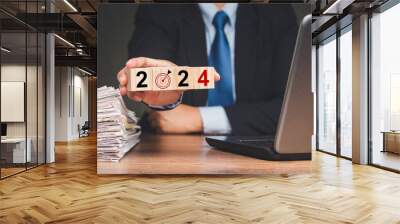 Hand businessman holding wooden cubes with the letters 2024 while sitting at the table Wall mural